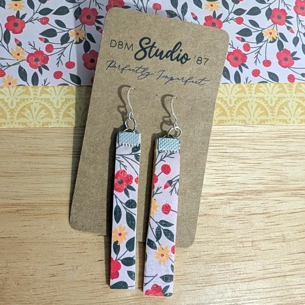 Slim, lightweight dangle earrings featuring a soft floral pattern with red and yellow blossoms on the front finished with silver-tone hooks.